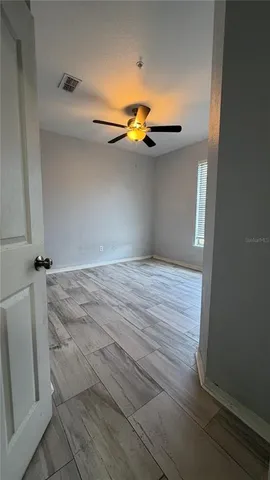 an empty room with window and chandelier fan