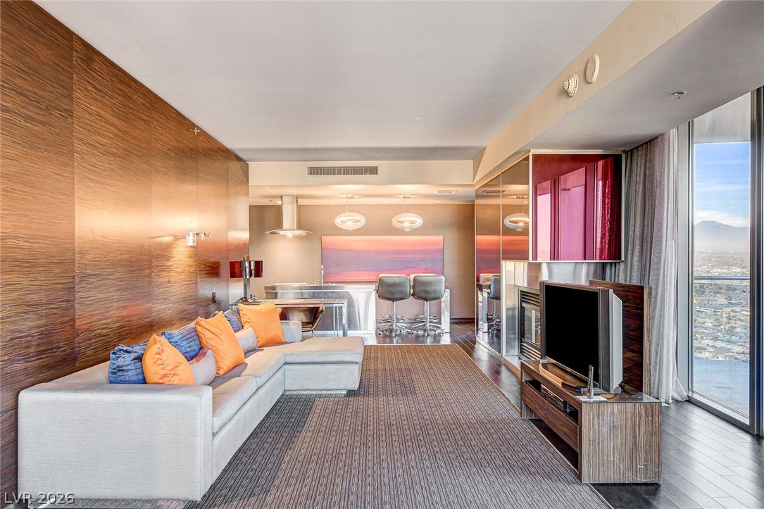4381 West Flamingo Road, Unit 3002 Las Vegas, NV 89103 - Photo 14 of 59 Gleaming wood paneling and massive floor-to-ceiling windows elevate this modern open-concept living space.