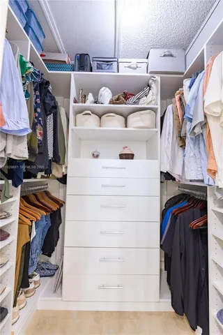 a view of walk in closet with clothes and shoes