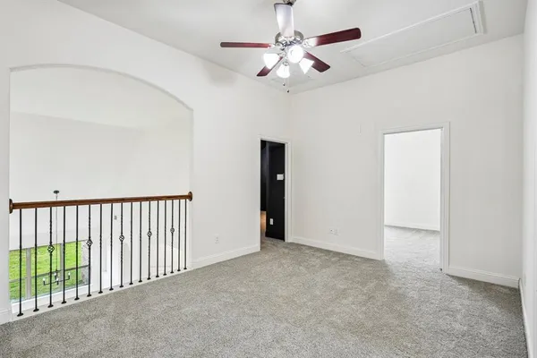 an empty room with chandelier fan and windows
