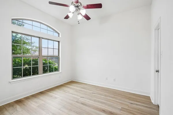 an empty room with wooden floor closet and windows