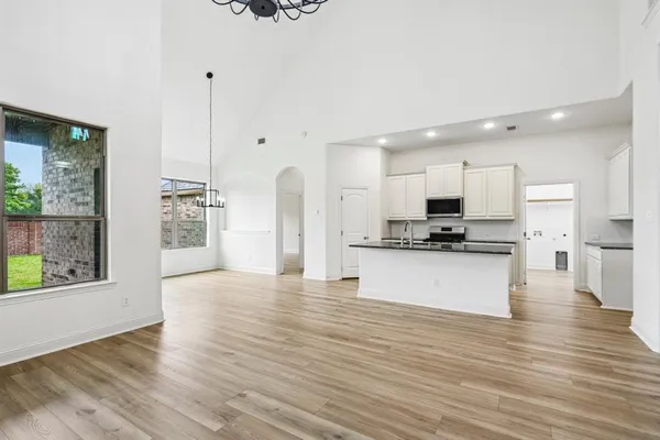 a view of kitchen with granite countertop stainless steel appliances refrigerator oven stove and white cabinets with wooden floor