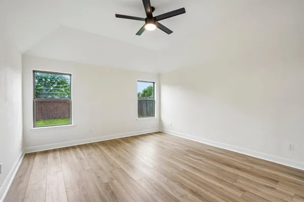 an empty room with wooden floor and windows