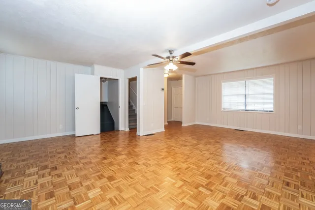 a view of an empty room with window and chandelier fan
