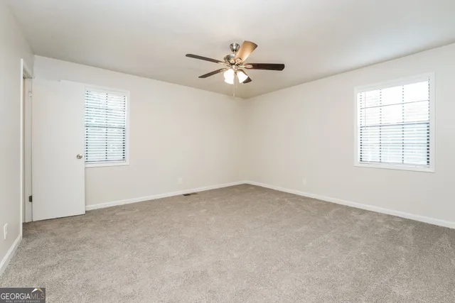 an empty room with windows and fan