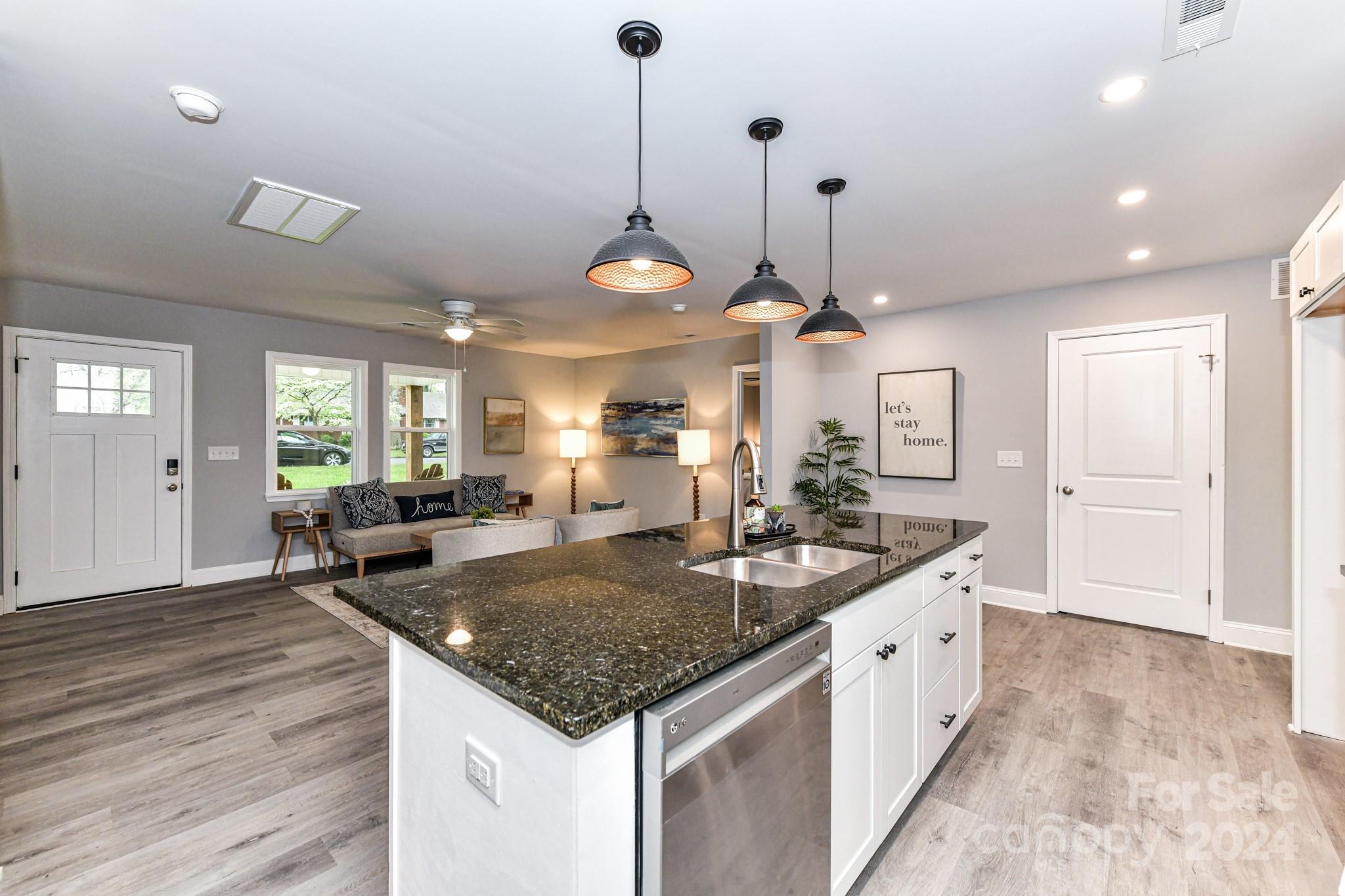136 Spencer Avenue Northwest Concord, NC 28025 - Photo 15 of 43 a kitchen with granite countertop a stove a sink a dining table and chairs with wooden floor