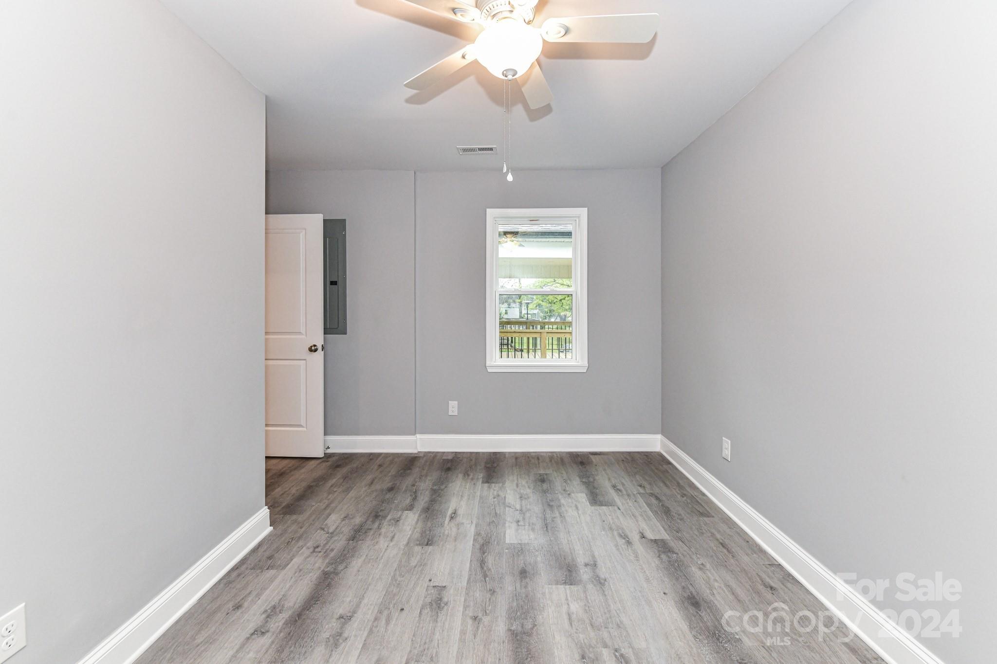 136 Spencer Avenue Northwest Concord, NC 28025 - Photo 27 of 43 an empty room with wooden floor chandelier fan and windows