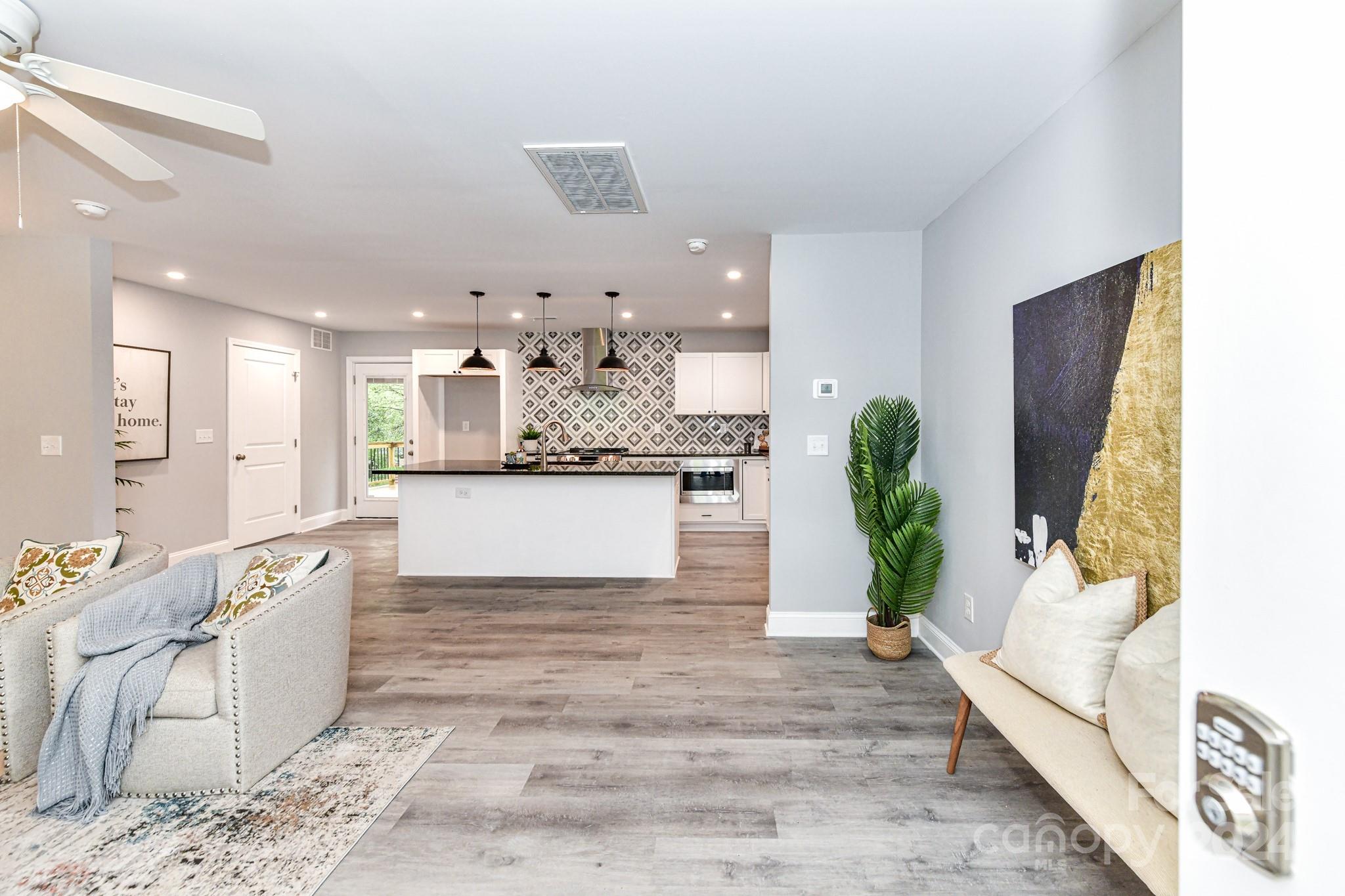 136 Spencer Avenue Northwest Concord, NC 28025 - Photo 4 of 43 a large white kitchen with stainless steel appliances kitchen island granite countertop a refrigerator a stove a sink and dishwasher with wooden floor