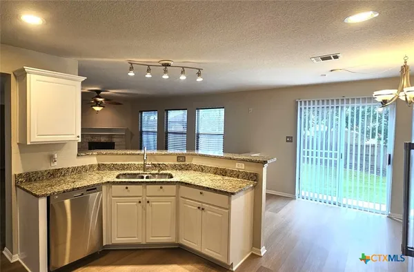 a open kitchen with granite countertop a sink and white cabinets with wooden floor