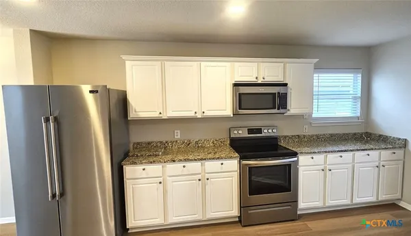 a kitchen with white cabinets and stainless steel appliances