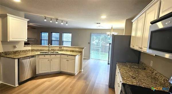 a kitchen with stainless steel appliances granite countertop a refrigerator a stove and a wooden floors