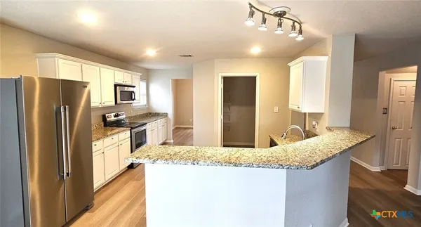 a kitchen with stainless steel appliances granite countertop a sink refrigerator and microwave