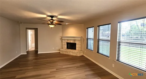 a view of a livingroom with a fireplace a ceiling fan and windows