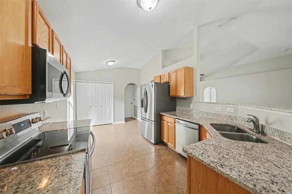 2212 Nicollett Way Leesburg, FL 34748 - Photo 12 of 26 a kitchen with stainless steel appliances granite countertop a sink stove and refrigerator