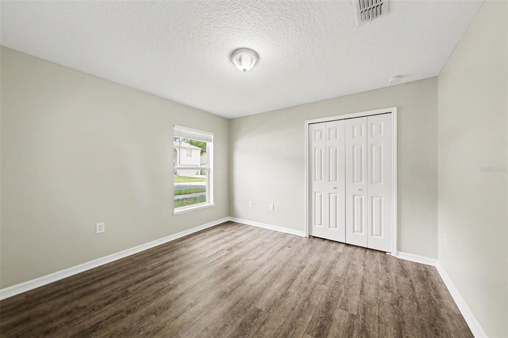 2212 Nicollett Way Leesburg, FL 34748 - Photo 4 of 26 an empty room with wooden floor and windows