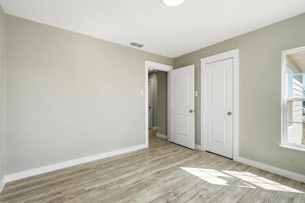 an empty room with wooden floor and windows