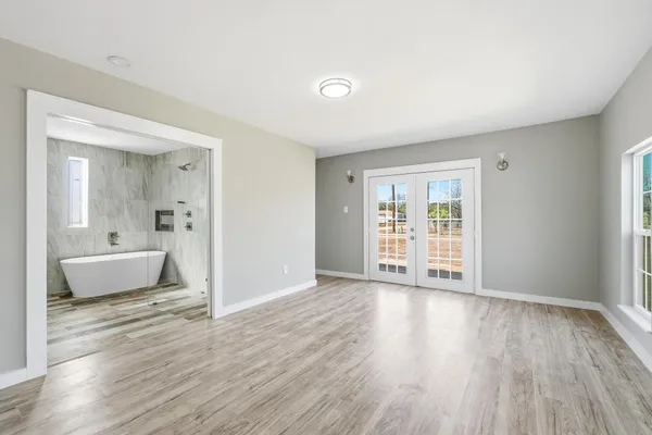 an empty room with wooden floor and windows