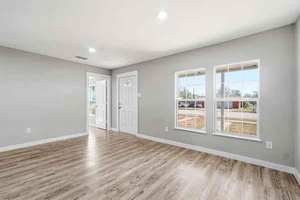 a view of an empty room with wooden floor and a window