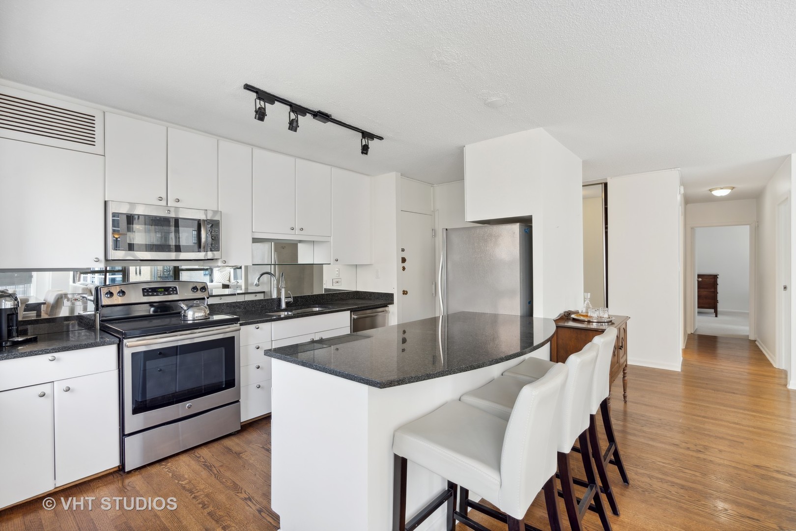 1313 North Ritchie Court, Unit 1304 Chicago, IL 60610 - Photo 9 of 20 a kitchen with stainless steel appliances granite countertop a stove a sink a microwave a refrigerator white cabinets and wooden floor