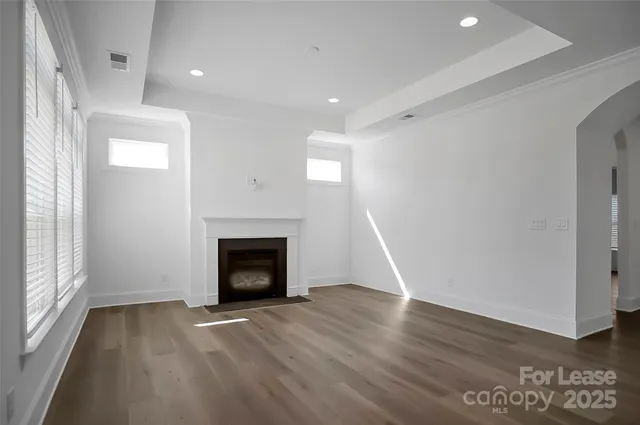 an empty room with wooden floor fireplace and windows