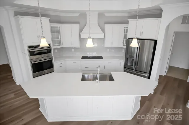 a kitchen with stainless steel appliances a refrigerator a stove a sink and white cabinets