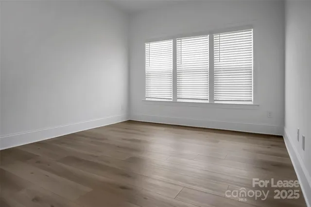 an empty room with wooden floor and window