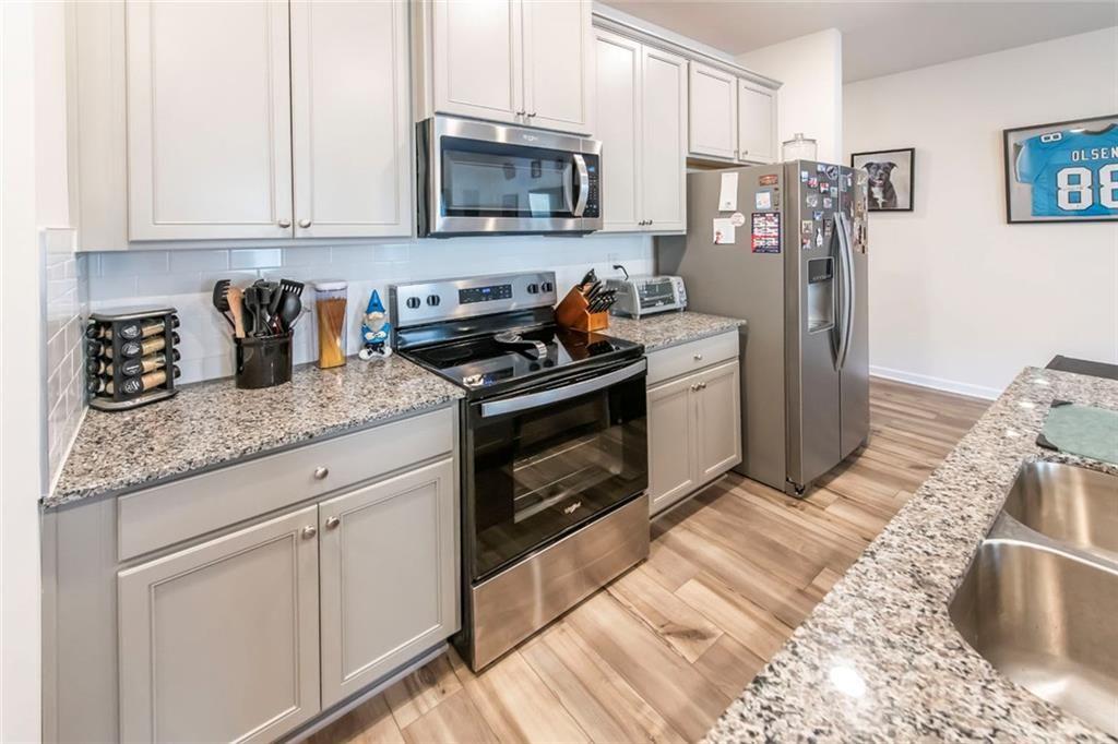 1182 Westhampton Way Villa Rica, GA 30180 - Photo 8 of 26 a kitchen with granite countertop a sink stove and refrigerator
