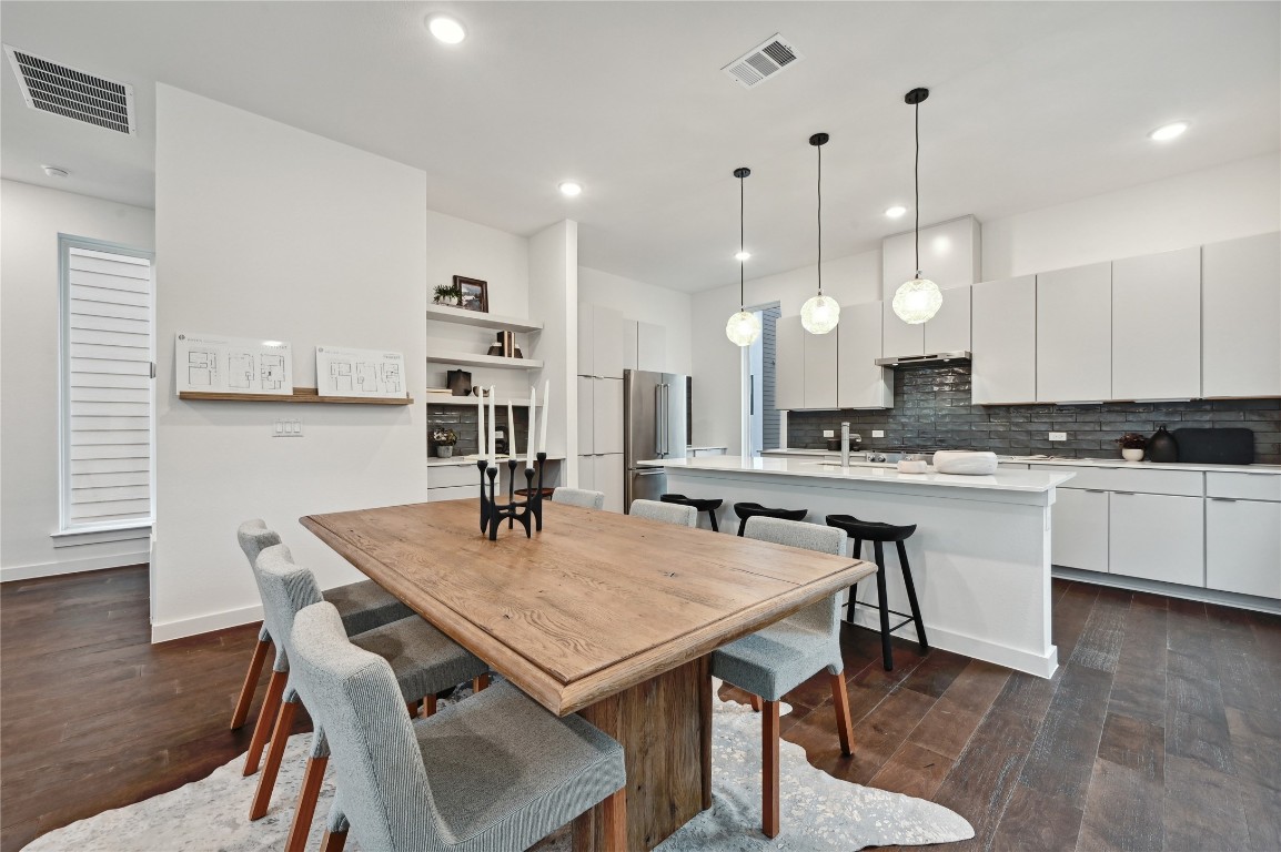 6821 Wolfcreek Pass, Unit 12 Austin, TX 78749 - Photo 13 of 32 a kitchen with granite countertop a table chairs stainless steel appliances and wooden floor