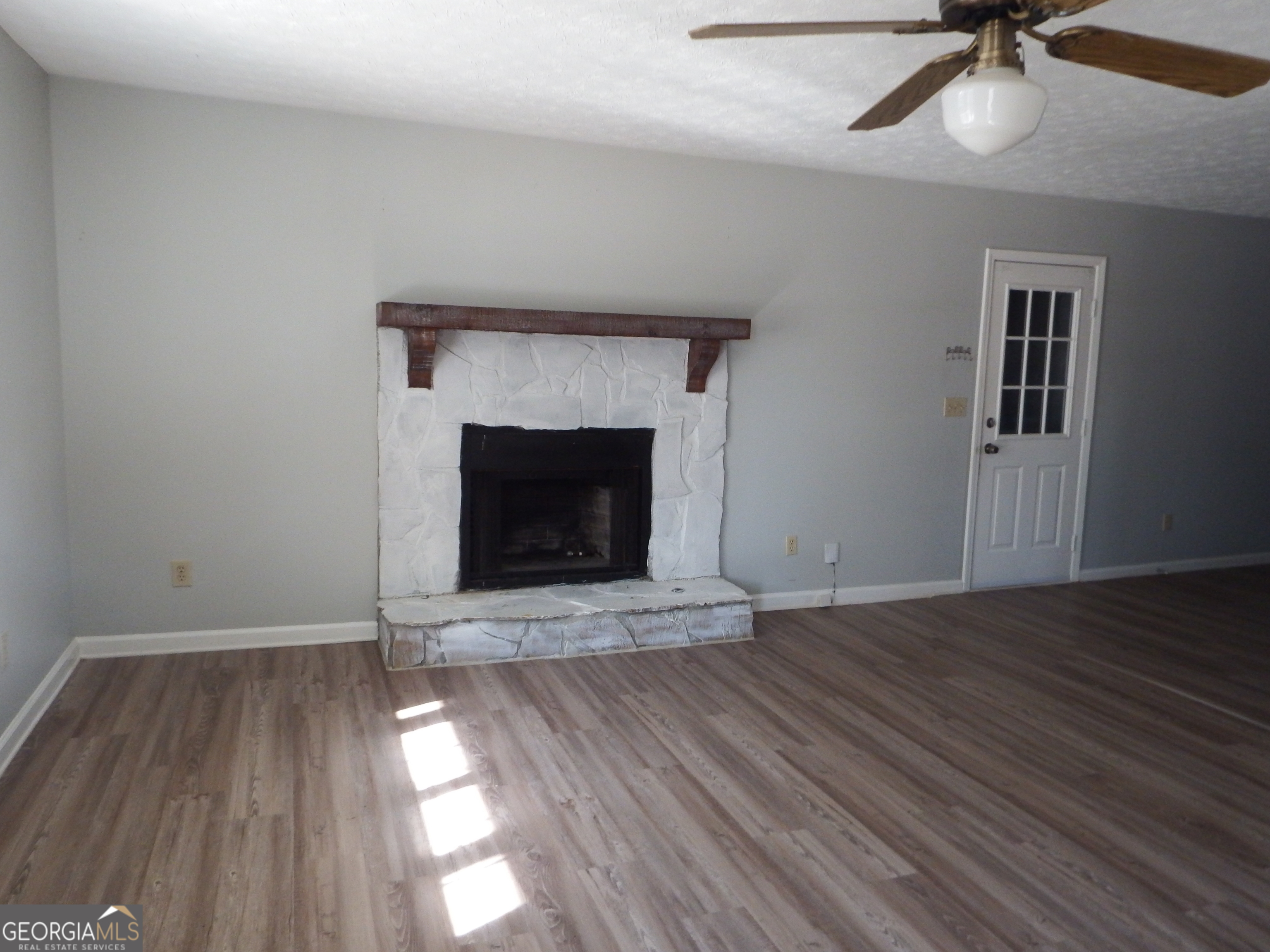 2780 Highpoint Road Snellville, GA 30078 - Photo 9 of 12 an empty room with wooden floor a fireplace and windows