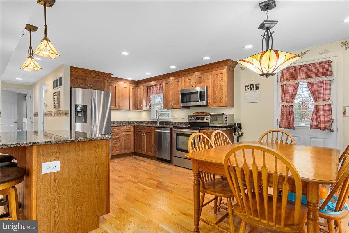 11701 Walnut Point Road Hagerstown, MD 21740 - Photo 18 of 56 a kitchen with stainless steel appliances granite countertop a refrigerator a stove top oven a sink dishwasher and a dining table with wooden floor