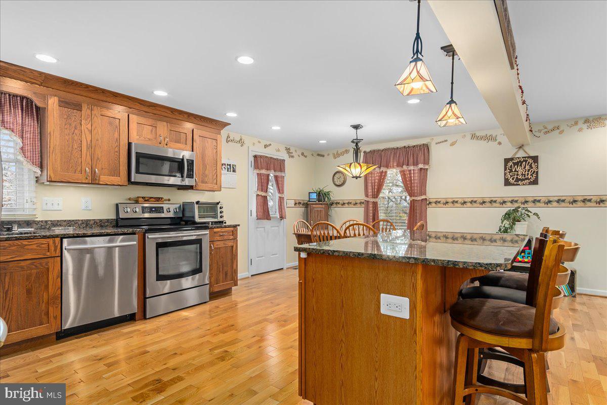 11701 Walnut Point Road Hagerstown, MD 21740 - Photo 20 of 56 a kitchen with stainless steel appliances granite countertop a stove top oven a sink a dining table and chairs with wooden floor
