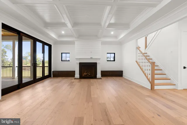 a view of an empty room with wooden floor fireplace and a window