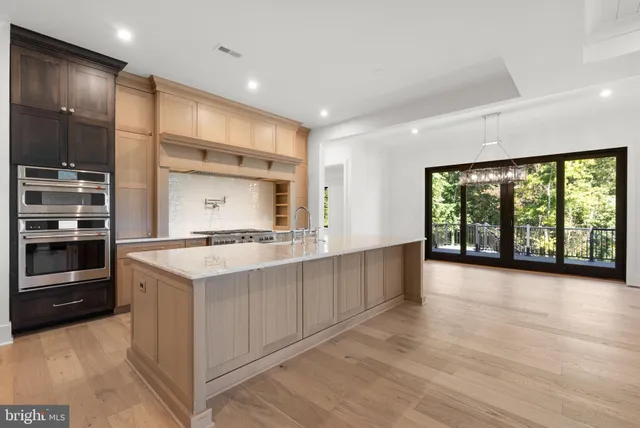 a large kitchen with stainless steel appliances a large counter top a stove and a refrigerator