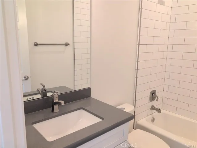 a bathroom with a tub sink vanity and toilet