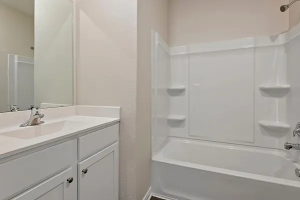 a bathroom with a granite countertop sink and a bathtub