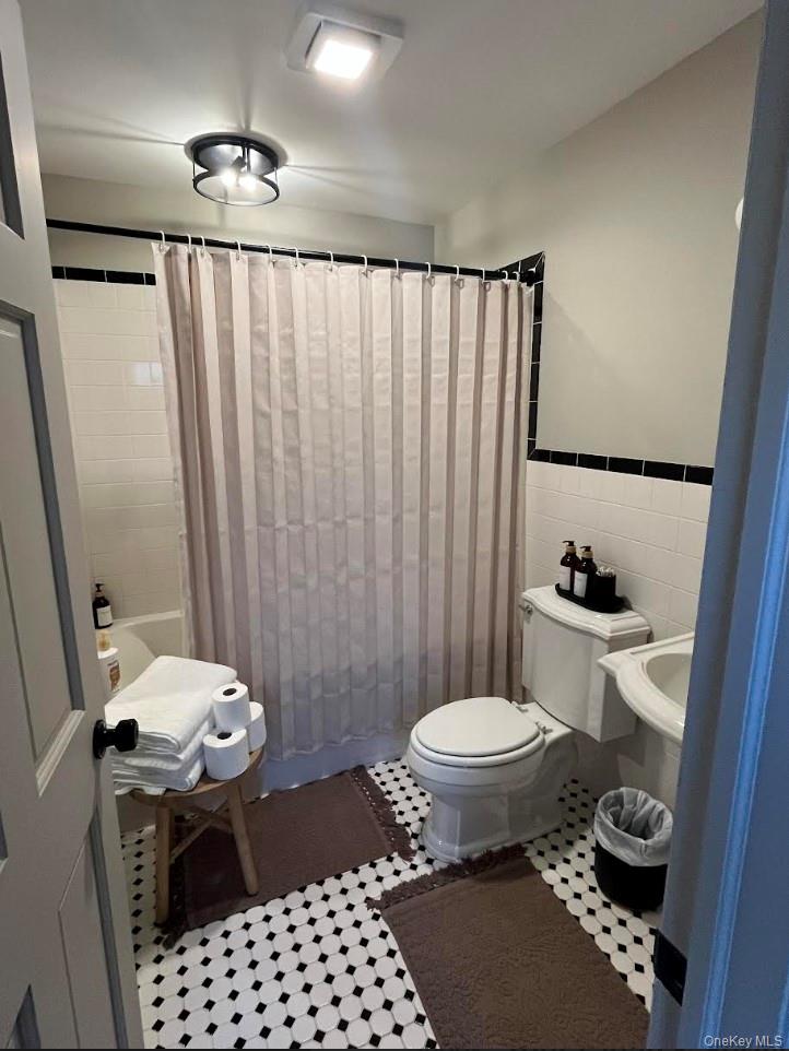 2039 Salt Point Turnpike Salt Point, NY 12578 - Photo 40 of 45 Bathroom with tile walls, tile patterned floors, a wainscoted wall, and shower / bath combo