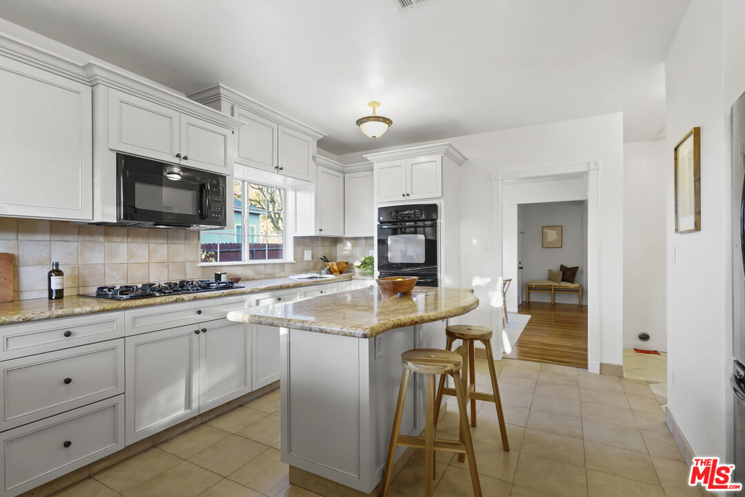 10129 Plainview Avenue Tujunga, CA 91042 - Photo 19 of 51 a kitchen with stainless steel appliances granite countertop a stove top oven a sink a microwave and a refrigerator