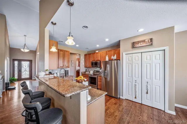 a open kitchen with a refrigerator a stove and a sink with wooden floor