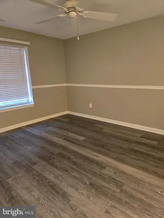 an empty room with wooden floor and fan