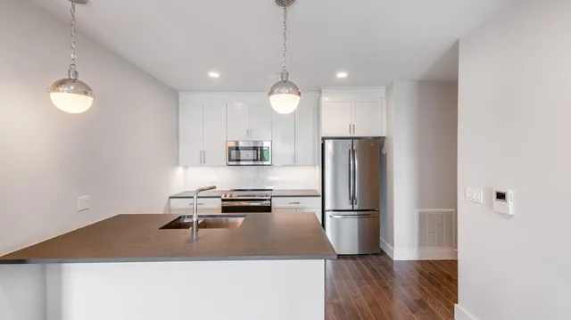 a kitchen with kitchen island white cabinets stainless steel appliances and wooden floor