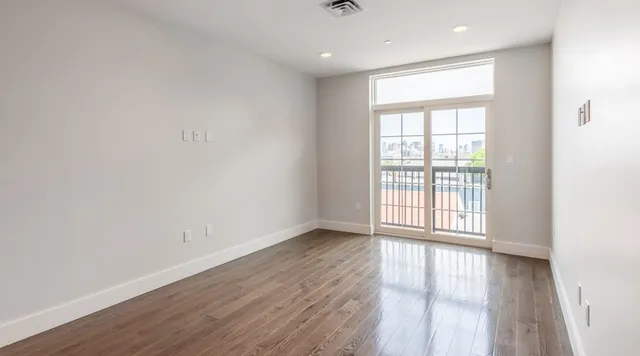 an empty room with wooden floor and windows