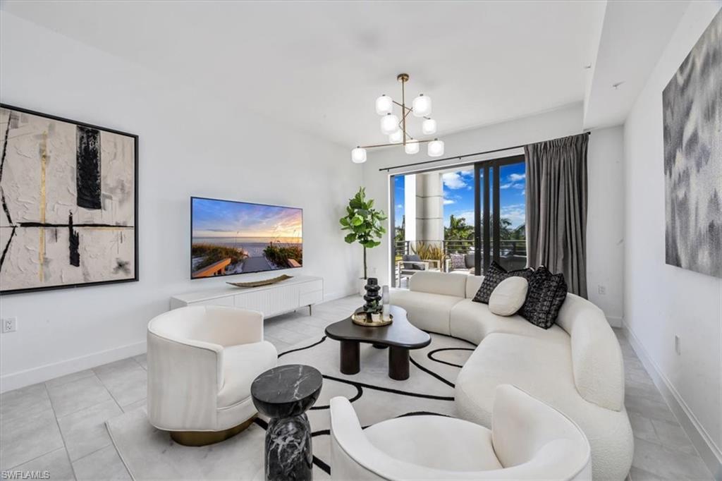 1111 Central Avenue, Unit 401 Naples, FL 34102 - Photo 11 of 36 a living room with furniture a chandelier and a flat screen tv