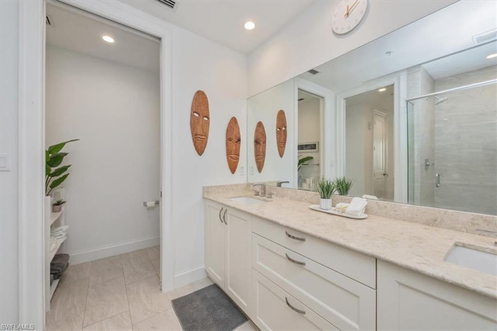 1111 Central Avenue, Unit 401 Naples, FL 34102 - Photo 16 of 36 a bathroom with a granite countertop sink a mirror and a shower