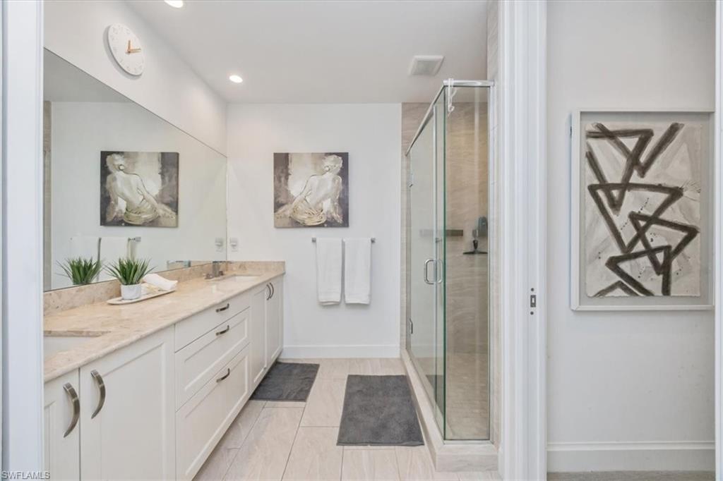 1111 Central Avenue, Unit 401 Naples, FL 34102 - Photo 18 of 36 a bathroom with a granite countertop sink a mirror a vanity and shower