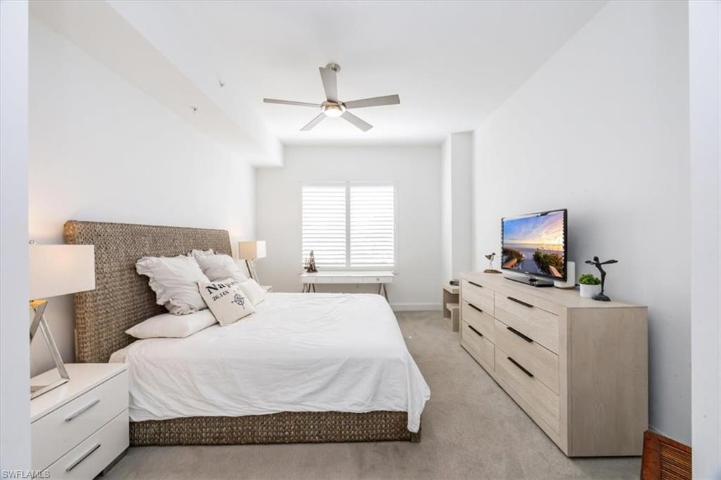 1111 Central Avenue, Unit 401 Naples, FL 34102 - Photo 21 of 36 a bedroom with a large bed and a flat screen tv