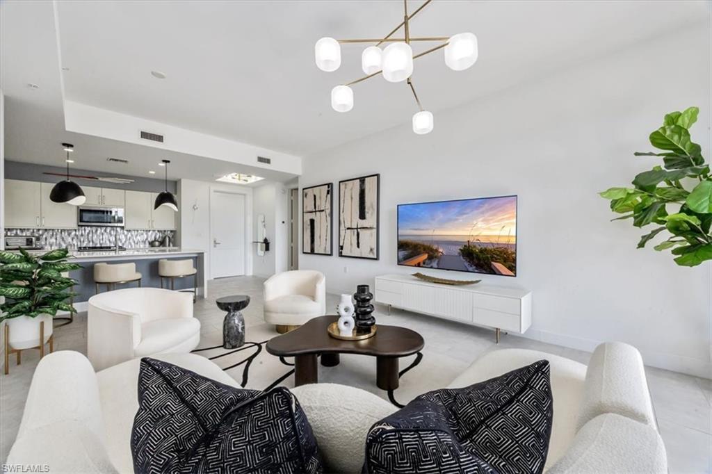 1111 Central Avenue, Unit 401 Naples, FL 34102 - Photo 4 of 36 a living room with furniture a chandelier and a flat screen tv