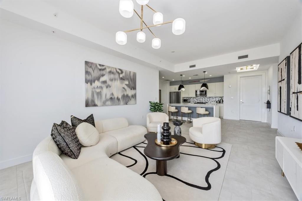 1111 Central Avenue, Unit 401 Naples, FL 34102 - Photo 6 of 36 a living room with furniture a rug and a chandelier