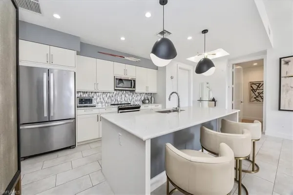 a kitchen with stainless steel appliances kitchen island granite countertop a sink and a refrigerator