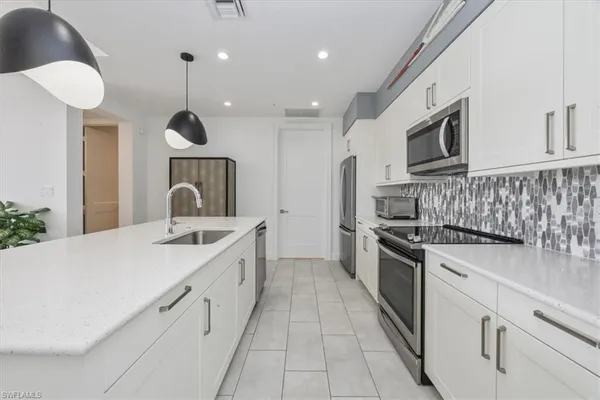 a kitchen with stainless steel appliances kitchen island granite countertop a sink and a refrigerator