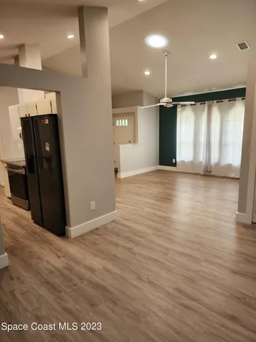 an empty room with wooden floor fan and windows